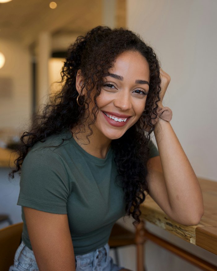 Portrait d'Awa Diallo, souriante, assise à une table en bois