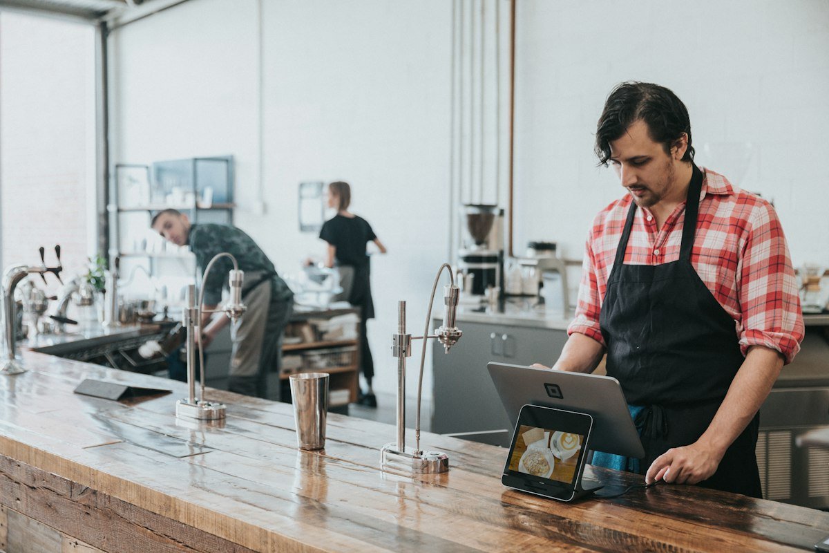 Un barista encaisse une commande sur une tablette au comptoir