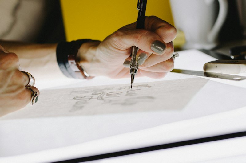 Une main trace des lettres au crayon sur du papier calque